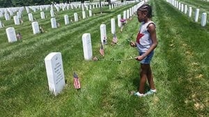 African American female child standing in front of a gravestone at the National Memorial Cemetary, Arlington, Virginia