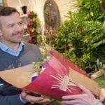 stock image smiling man gray sweater purchasing flowers