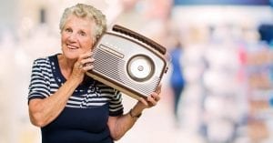 Old Caucasian lady holding a radio to her ear. 