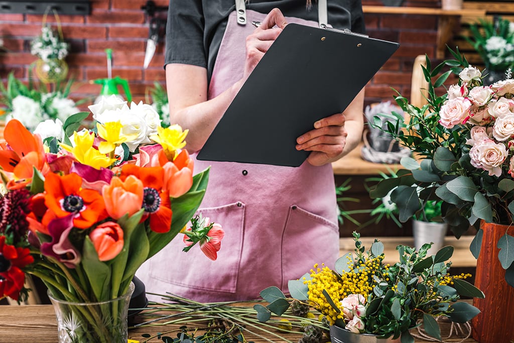 Florist counts and records flowers in florist shop