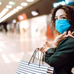 Young woman wearing protection face mask against coronavirus after shopping in the mall. Purchases, shopping, lifestyle concept. Covid-2019.